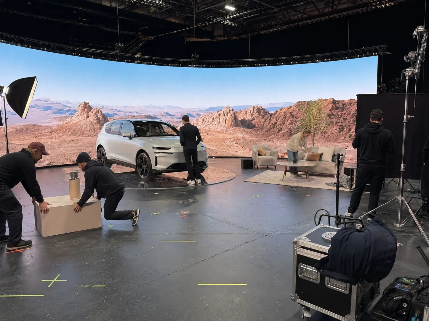 A film crew setting up lighting and camera equipment on a virtual production studio stage