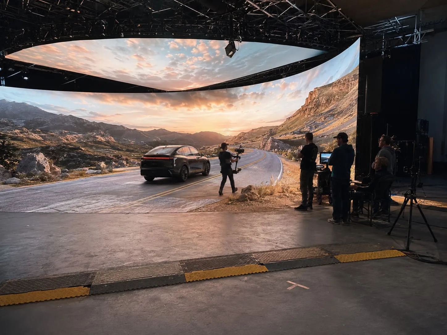A cinema camera filming a car driving on a dramatic scenic route on an LED volume