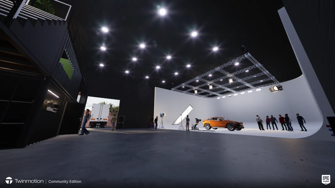 Studio scene with an orange car under bright lights. People observe and film. Black interior, high ceiling, and a truck in the background.