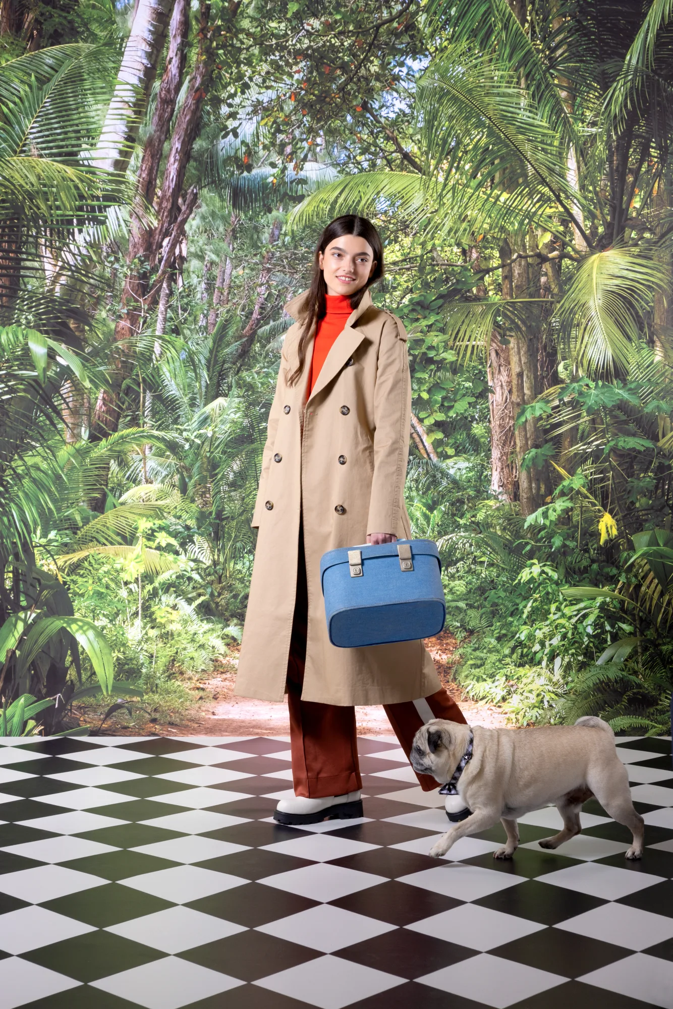 Woman in beige trench coat holding a blue bag, walking a pug on black-and-white checkered floor. Jungle backdrop with lush green leaves.