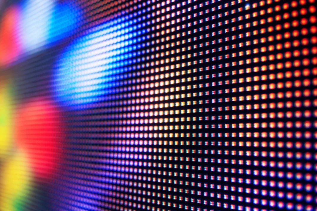 Close-up of a colorful LED screen with bright dots forming a gradient of blue, red, and yellow hues, creating a vibrant digital pattern.